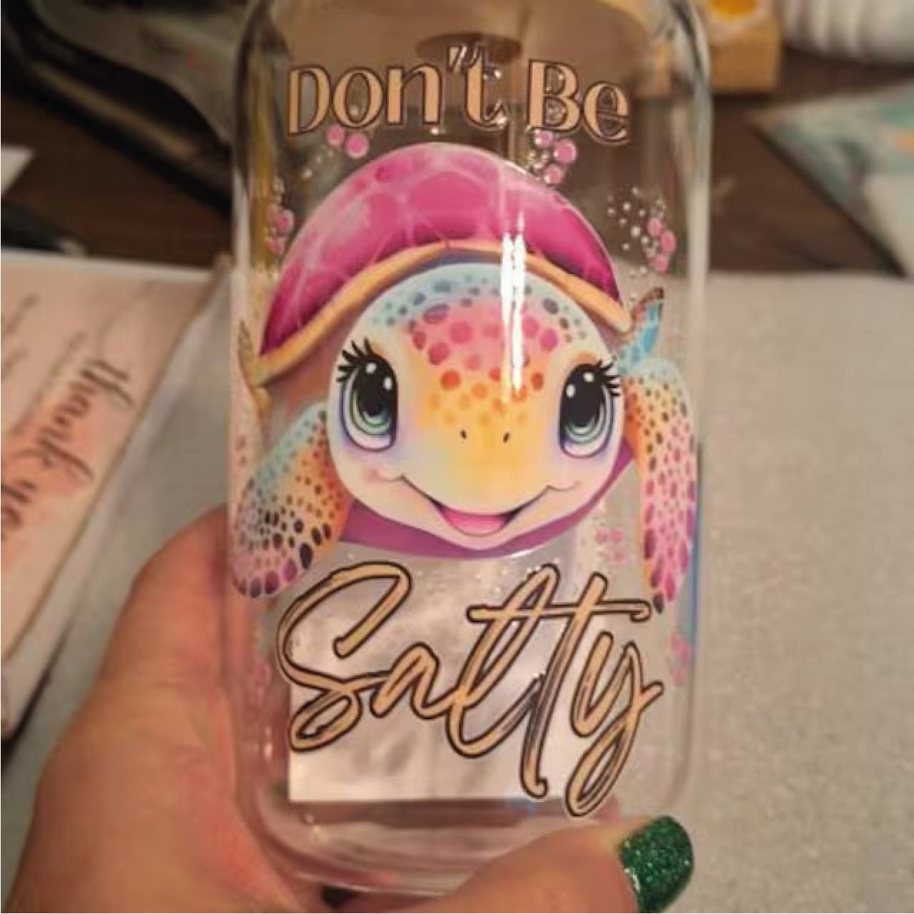 a person holding a glass with a picture of a turtle on it