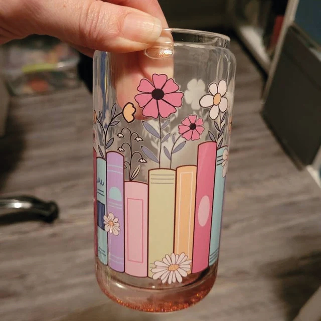 a hand holding a glass with a painting on it
